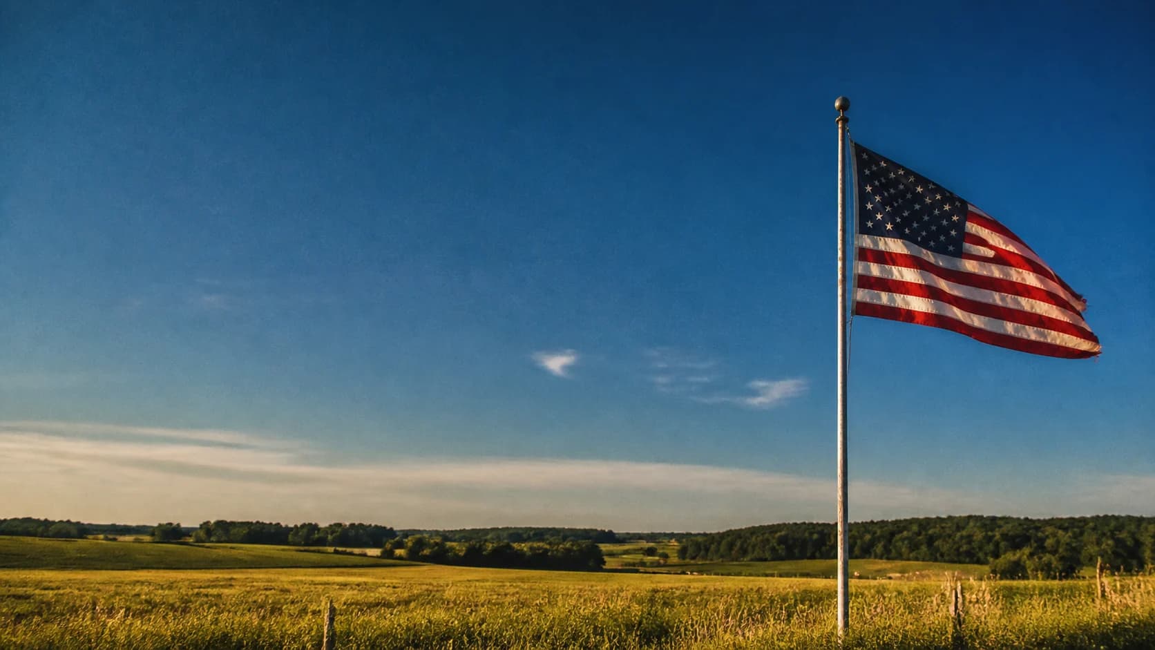 An American flag above an open, sunlit field